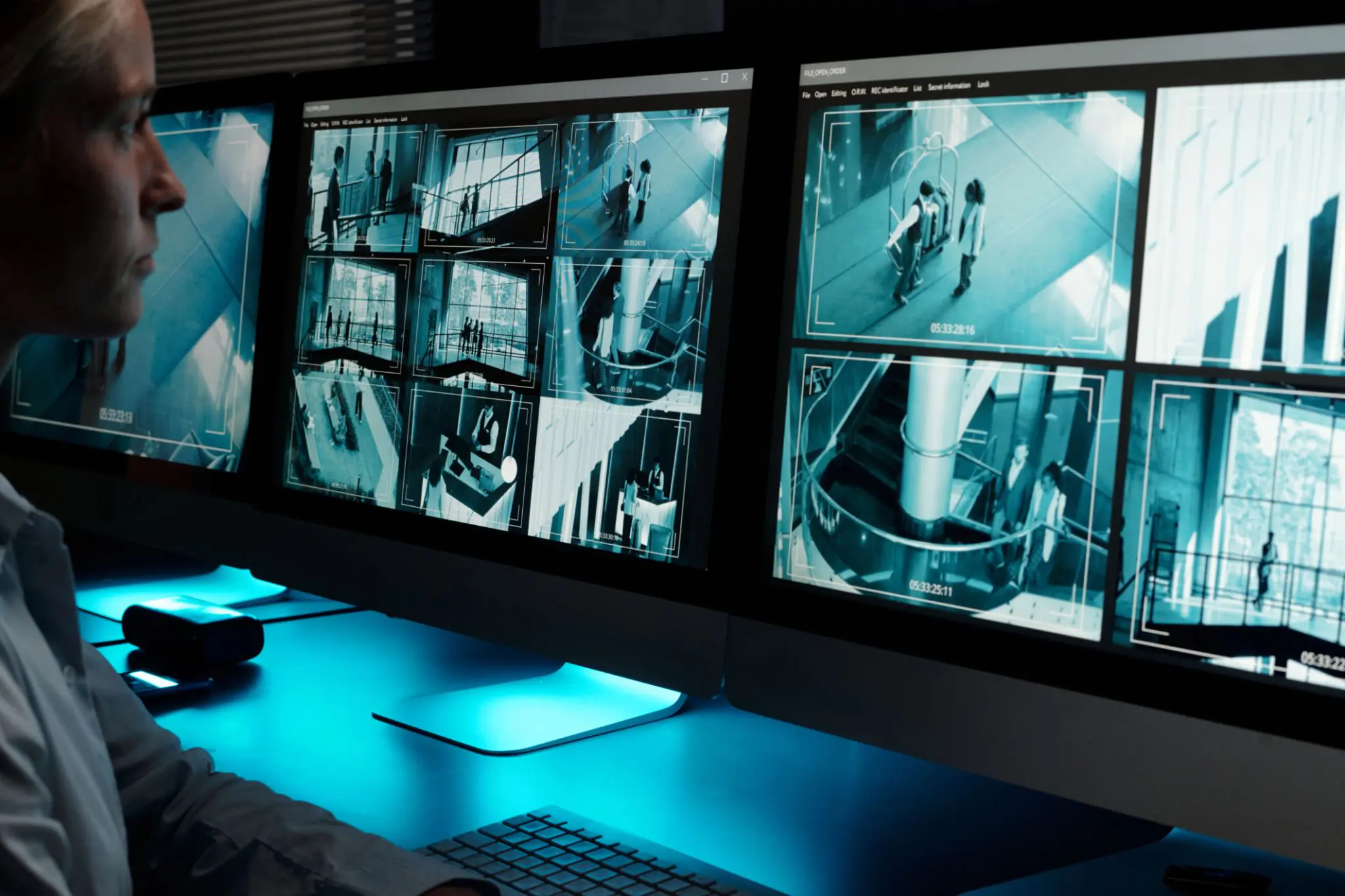 Person monitoring multiple security camera screens.